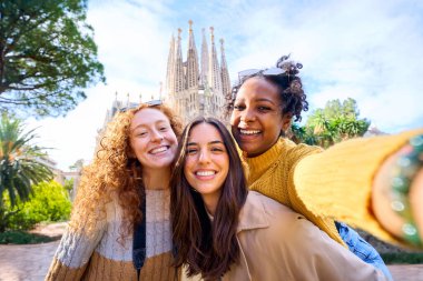 Barcelona 'da Sagrada Familia' nın önünde selfie çeken genç ve komik kadınlar. Avrupa sokaklarındaki güzel melez kız tatilin tadını çıkarıyor ve gülümsüyor. Komik turizm insanları.