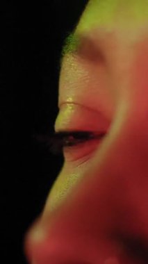 TV yansımasının renkli neon ışığı ile kadınların gözlerini dikey olarak kapat. Güzel Afro-Amerikan Kız dijital ekranı izliyor. Cilt Kadın yüzünde yanıp sönen Çoklu Renkler.