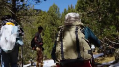 Tatilde kar dağında yürüyüş yapan bir grup insan. Çok ırklı arkadaşlar orman manzarasının tadını çıkarıyorlar.