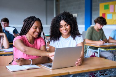 Öğrenciler sınıfta bilgisayar laptopuyla çalışıyorlar. Gençler birlikte vakit geçiriyorlar. Genç ve neşeli Afrikalı Amerikalı kız birlikte çalışıyor. Yüksek kalite fotoğraf
