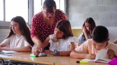 Bir öğretmen sınıftaki bir öğrenciye bireysel rehberlik eder, katılımını teşvik eder ve öğretici ve destekleyici bir öğrenme ortamında anlayış gösterir.