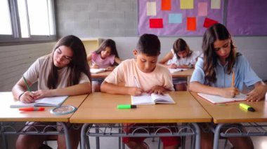 Sınıfta birlikte çalışan bir grup çok ırklı öğrencinin ön görüntüsü. Sahne odaklanma, işbirliği ve akademik ortamda genç öğrencilerin çeşitliliğini vurguluyor