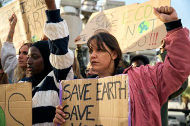 Farklı yaşlardan çok ırklı aktivist bir grup insan fabrikaları ve kirliliği protesto etmek için toplandı. Dünya 'nın lehine iklim değişikliği pankartlarıyla tezahürat