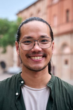 Dikey. Yakışıklı, mutlu, sakallı Asyalı adam. Açık havada durup kameraya gülümseyen neşeli genç Çinli erkek portresi. Pozitif duygu kavramı. Milenyum erkeği kaygısız ve doğal görünüyor..