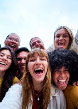 Genç, çok ırklı ve güzel arkadaşların dikey selfie 'si dışarıda birlikte eğleniyorlar. Mutlu kameraya bakan heyecanlı insanlar güneşli bir günde şehri gezmekten zevk alıyorlar. Z nesli ve tatiller