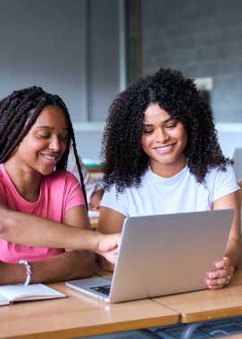 Dikey. Öğrenciler sınıfta bilgisayar laptopuyla çalışıyorlar. Gençler birlikte vakit geçiriyorlar. Genç ve neşeli Afrikalı Amerikalı kız birlikte çalışıyor. Yüksek kalite fotoğraf