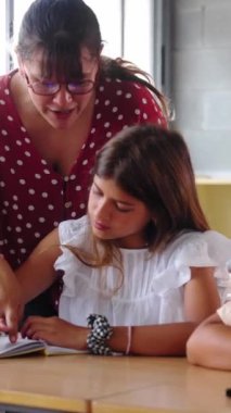 Dikey. Bir öğretmen sınıftaki bir öğrenciye bireysel rehberlik eder, katılımını teşvik eder ve öğretici ve destekleyici bir öğrenme ortamında anlayış gösterir.