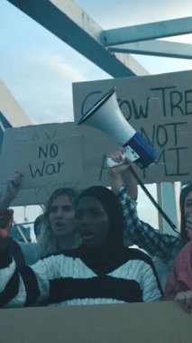 Dikey genç kadın, savaşlara karşı öfkeli sloganlarla bağırıyor çeşitli gruplarla protesto yapıyor barış için pankartlar taşıyor, dışarıda yürüyen ordular değil.