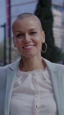 Dikey. Orta yaşlı beyaz iş kadını kameraya gülümsüyor. Neşeli Avrupalı kadın arka planda bulanıklık var. Olumlu ifadeli mutlu, tıraşlı, beyaz bir insan. Kırklar