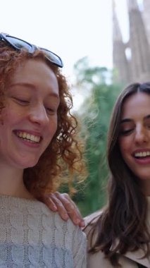Dikey. Barcelona 'da Sagrada Familia' nın önünde el ele gezen tek genç bayan arkadaş. Avrupa 'daki güzel beyaz kızlar tatilin tadını çıkarıyorlar ve gülümsüyorlar. Turizm insanları