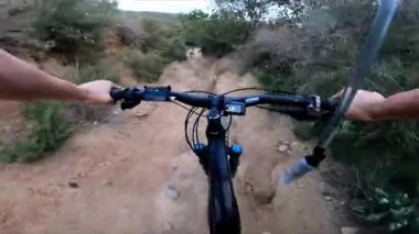 Tanımlanamayan dağ bisikletçisinin POV 'u yokuş aşağı çalılıklarda kayalık yolda hızla gidiyor. Maceraperest bisikletçilerin gidonlarının arkasında yazın aşırı riskli açık hava sporları yapan bir bakış açısı. 