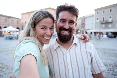 Kalabalık bir kasaba meydanında selfie çeken mutlu turistler, birlikte gülümseyerek ve tatillerinin tadını çıkararak, canlı bir Avrupa şehrini keşfederken kalıcı anılar yaratıyorlar.