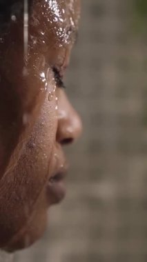 Dikey. Genç, Afro-Amerikan bir kadının evinde sakin bir duş alışı. Güzel kadın duş alıyor, saçlarını yıkıyor dinlenme zamanının tadını çıkarıyor, damlalar ve su vücuduna akıyor.