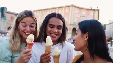 Üç genç kadın dondurma külahlarının keyfini çıkarıyorlar. Avrupa 'nın canlı şehir merkezinde yaz tatili maceraları boyunca gülüyorlar ve keyifli anları paylaşıyorlar.