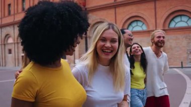 Bir grup neşeli üniversite arkadaşı sokakta yürüyorlar, birlikte gülüyorlar ve eğleniyorlar.