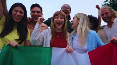 İtalyan bayrağını gururla tutan çok ırklı bir arkadaş grubu vatanseverliği ve sporu, futbolu kutluyorlar. Neşeli hava, birlik, coşku ve kültürel gurur gösterisi.