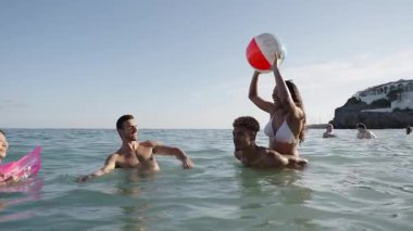 Bikinili mutlu gençler gün batımında denize koşup şişme top oynuyorlar. Neşeli bayan arkadaşlar gölette su sıçratarak eğleniyorlar. Genç kadınlar yüzmeye gider, gölde yıkanırlar. Yavaş çekim