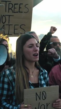 Dikey. Farklı gruplardan insanlarla büyümüş, dışarıda savaş karşıtı bağırışları protesto eden Z nesli kadın. Dünya Barış Yürüyüşü gösterilerinde savaş karşıtı pankartlarla ayakta duran aktivistler