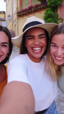 Yaz kıyafetleri içinde gülümseyen üç genç hippi kadın. Akıllı telefondan kendi portresini çeken kızlar. Sokakta poz veren mankenler. Olumlu yüz ifadeleri gösteren bir kadın. Yüksek kalite fotoğraf