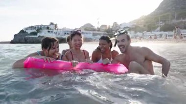 Mayo giymiş, birbirine gülen ve sahilde eğlenen bir grup çok ırklı genç. Nesiller boyu neşeli arkadaşlar güneşli yaz tatillerinde birlikte eğleniyorlar.