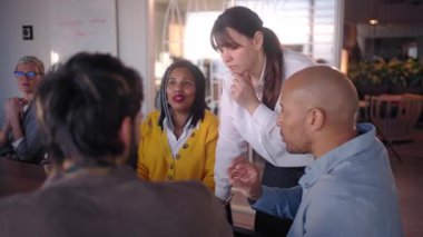 Profesyonel iş kadını işbirlikçi ekip toplantısına liderlik ediyor, çeşitli meslektaşlar stratejik beyin fırtınası yapıyor ve modern ofis ortamında yenilikçi fikirleri paylaşıyor.