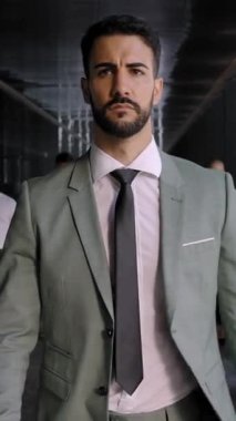 Dikey. Kendine güveni olan yakışıklı yetişkin bir adam ofis koridoruna doğru yürürken çeşitli meslektaşları kalabalıklaştı. Çekici, başarılı, takım elbiseli bir yönetici ciddi bir şeye bakıyor.