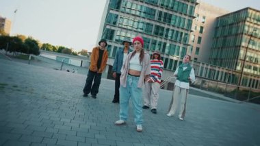 Vahşi bakışları ve sokak tavırları olan şehir gençleri kameraya doğru kasıla kasıla yürür, modern bir şehrin arka planında kendine güvenen şık bir kadının etrafında toplanır.