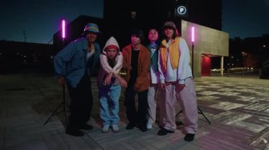 Genç şehir dansçıları geceleri arka planda canlı neon ışıklarıyla performans sergiliyorlar, enerjik hip hop hareketlerini çarpıcı renklerle ve modern sokak tarzıyla harmanlıyorlar.