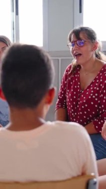 Dikey. Çeşitli gençlerle grup terapi seanslarına öncülük eden okul danışmanı. Sınıfta sandalyelerde oturup açık iletişim ve duygusal destek sağlıyorlar.