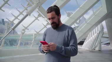 Valencia 'daki bilim parkında cep telefonu kullanan yakışıklı bir beyaz adam. Gülümseyen genç yetişkin dışarıda seyyar daktilo kullanıyor. Telefona cevap veren erkek. İletişim kuran insanlar.