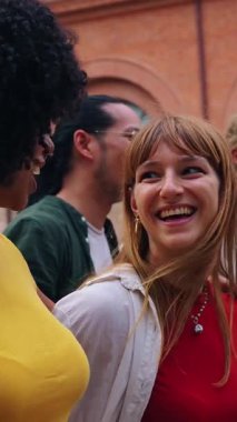 Dikey. Bir grup neşeli üniversite arkadaşı sokakta yürüyorlar, birlikte gülüyorlar ve eğleniyorlar.