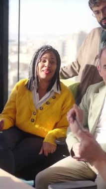 Dikey. Meslektaşlar gülümserken ve çalışmaya devam ederken pozitif enerji, işbirliği ve motivasyon gösteren, parlak, modern bir ofiste bir dönüm noktasını kutlayan çok kültürlü bir ekip..