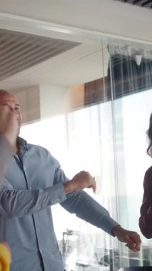 Dikey. Gülümseyen meslektaşlar, neşeli bir takım oluşturma anı boyunca birlikte kutlama yapıyorlar. Parlak, modern bir ofiste, dahil etme, motivasyon, birlik ve pozitif enerji iş yeri kültürünü güçlendiriyor.