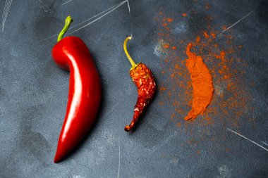 Çeşitli aşamalarda kırmızı biber. İşlenmemiş kırmızı biber, kurumuş ve koyu arkaplanda kırmızı biber tozu..