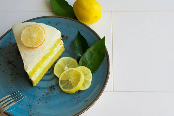 A piece of lemon cream cake on a plate, presentation of delicious sliced lemon cake, top view.