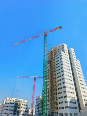 Construction of houses in Israel 2023. Two cranes next to boxes of houses, against a clear sky