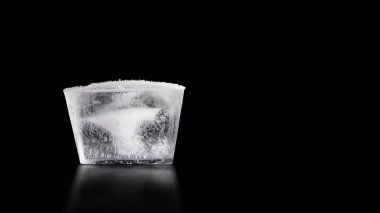 transparent ice cube with air patterns inside on isolated black background. There is an outline of the image clipart