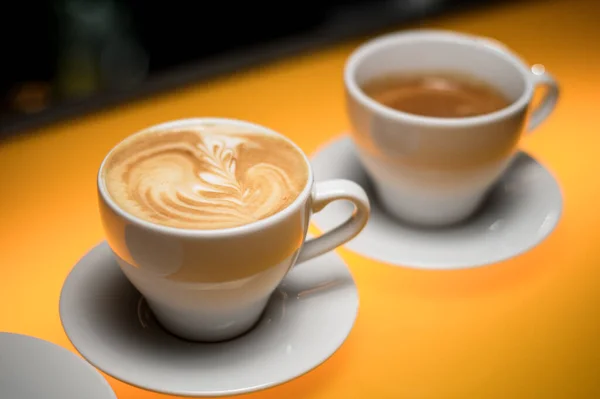 尽收眼底 白色杯子配上美味的咖啡 茶托放在黄桌上 拿铁艺术 — 图库照片