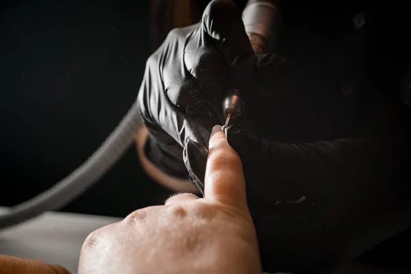 プロの電気ネイルドリルで女性の手に爪を優しく滅菌黒手袋のマニキュリスト — ストック写真