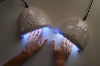 Tırnak cilasının üst kapağını iyileştirmek için dişi ellerinin ultraviyole lambaya girdiği harika bir manzara. Manikür, kaplıca salonu konsepti. Güzellik ve moda.