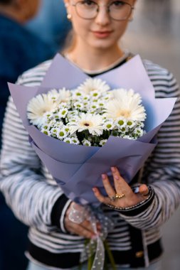 Güzel bir buket beyaz çiçek, Gerbera kasımpatı ve papatya çayı. Kadın ellerinde ambalaj kağıdı. Yakın plan.