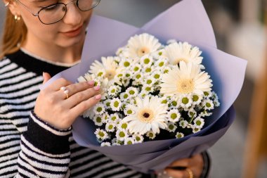 Güzel bir buket beyaz çiçekte yakın plan manzara gerbera chrysanthemum ve papatya kadın ellerinde ambalaj kağıdında..