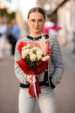 Elinde kırmızı ambalaj kağıdıyla beyaz güller olan güzel bir kadın.