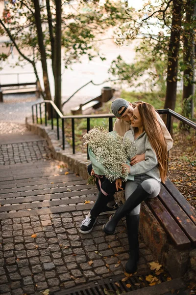 美しい若い女性と男がベンチの屋外に座っている 愛の抱擁とキスのカップル 彼女にキスして ラブストーリー — ストック写真