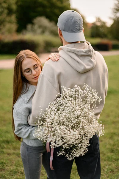 꽃다발을 어깨에 남자와 아름다운 여자의 뒤쪽을 바라본다 스토리 낭만적 — 스톡 사진