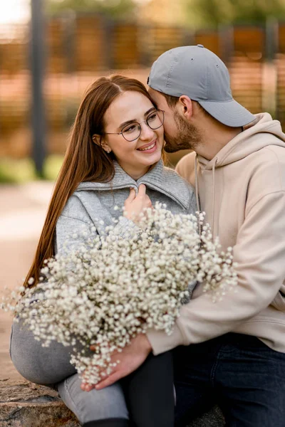 花の花束と男が彼女にキスで陽気な若い女性のクローズアップ ラブストーリー 愛の幸せなカップル ロマンチックなデート — ストック写真