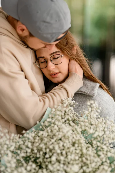 花束を持った眼鏡をかけた若い女性と頭を抱える男性のクローズアップ ロマンチックなデートだ ラブストーリー — ストック写真