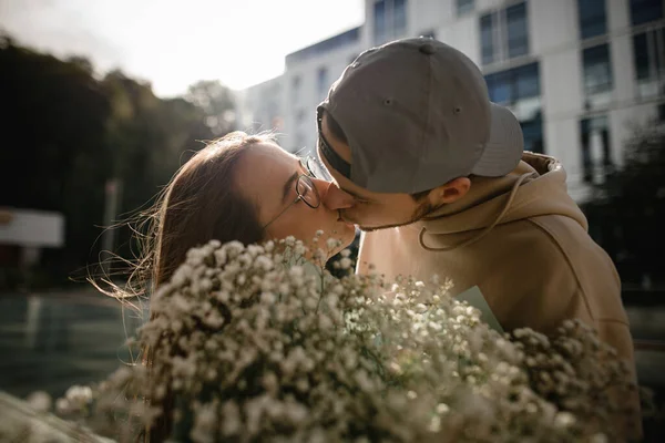 在亲吻年轻帅气的男男女女头上的美丽的特写镜头 前景暗淡的花卉花束 — 图库照片