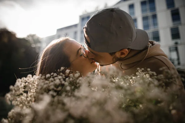 若い女性と男にキスする頭の素晴らしい肖像画 手前の花びらの花束 — ストック写真