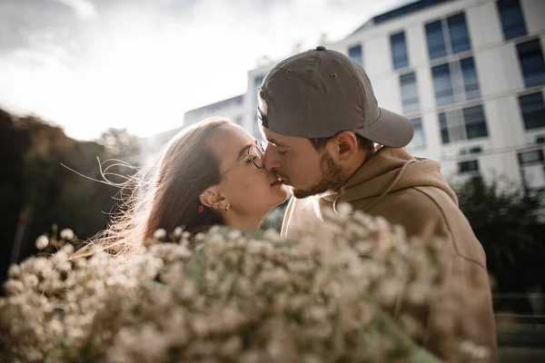 若い美しい女性と男にキスをする頭の上のクローズアップ側のビュー 前景に咲く花の花束 — ストック写真